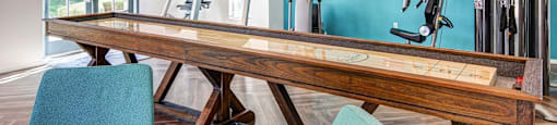 A room with a wooden table, two chairs, and exercise equipment.