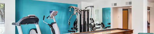 A gym with a treadmill, elliptical trainer, and other exercise equipment.