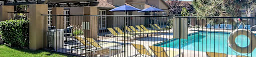 A pool area with a fence and a building in the background.