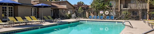 A large swimming pool with a slide and sun loungers.