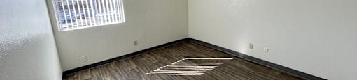 A room with wooden flooring and a window with blinds.