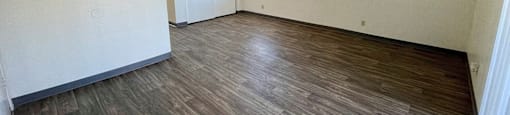 A room with wooden flooring and white walls.