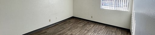 A room with wooden flooring and a window with blinds.
