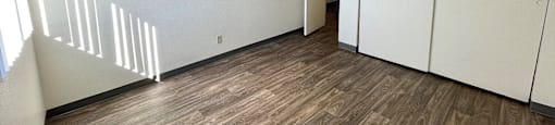 A room with wooden flooring and white walls.