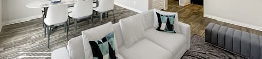 A living room with a white couch and a dining table with chairs.