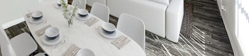 A modern dining room with a white table set for six.