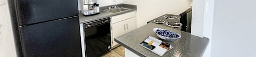 A black refrigerator is in a kitchen with white walls.