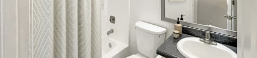 A white bathroom with a toilet, sink, and shower.