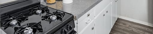 A kitchen with a black stove top and white cabinets.