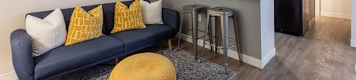 A blue couch with yellow pillows sits in a kitchen area.