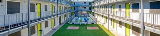 A long corridor with balconies on both sides and a green lawn in the middle.