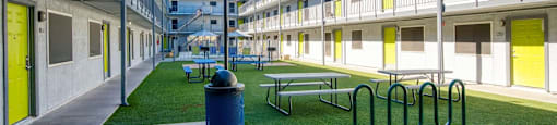 A sunny day at a modern apartment complex with green grass and yellow doors.