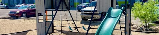 A playground with a green slide and a wooden structure.