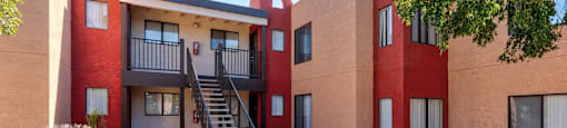 A red and beige building with a staircase leading to the entrance.