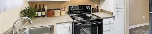 A kitchen with a black stove top oven and a silver sink.