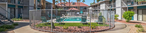 A pool surrounded by a fence and palm trees.