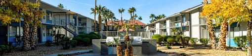 A courtyard with a fountain surrounded by palm trees and buildings.