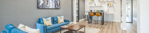 A living room with blue couches and a painting on the wall.