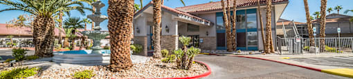 A building with a red roof is surrounded by palm trees.
