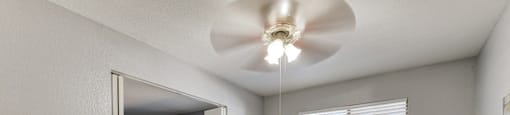 A bedroom with a bed, a ceiling fan, and a mirror.