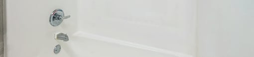 A white bathtub with a silver faucet and a silver drain.