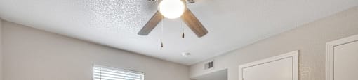 A room with a ceiling fan and two doors.