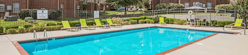 A swimming pool in a residential area with apartment buildings in the background.