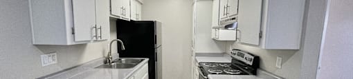 A kitchen with white cabinets and a black refrigerator.