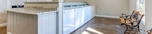 A kitchen with a white counter and a washing machine.