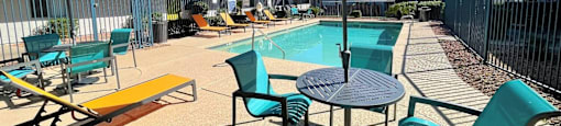 A sunny day at the pool with a striped umbrella providing shade.