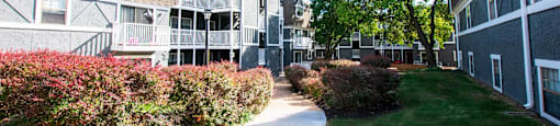 A pathway leads through a grassy area between two buildings.