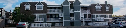 A large apartment building with a parking lot in front.