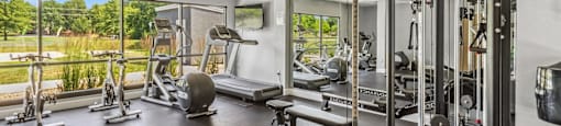 A gym with a variety of equipment including a weight bench, a leg press machine, and a cable machine.