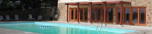 A view of the swimming pool with the clubhouse in the background at Cedar Ridge Apartments.