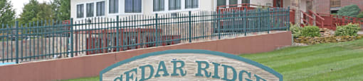 The welcome sign at Cedar Ridge Apartments, set against a green landscape.