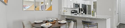 A modern kitchen with a dining table set for two.