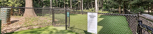 the dog park is fenced in with green grass and trees