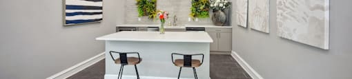 a kitchen with a white counter and three stools