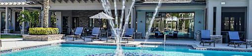 a large swimming pool with a fountain in front of a house