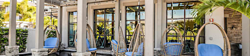 a patio with blue chairs and a pool