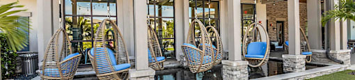 a row of wicker hammocks in a building with windows