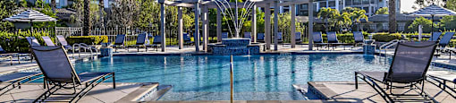 a large swimming pool with chairs and palm trees
