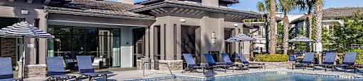 a large swimming pool in front of a house with chairs and a umbrella