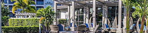 a patio with tables and chairs and a pavilion with palm trees