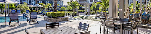 a covered patio with tables and chairs and a pool