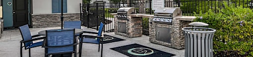a patio with a grill and chairs and umbrellas