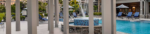 an outdoor pool with a fountain and lounge chairs