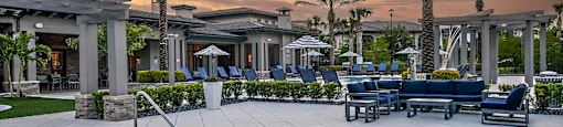a pool with blue chairs and a sunset in the background
