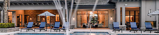 a large swimming pool with a fountain in front of a house