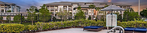 an outdoor hot tub with an umbrella in a resort style pool